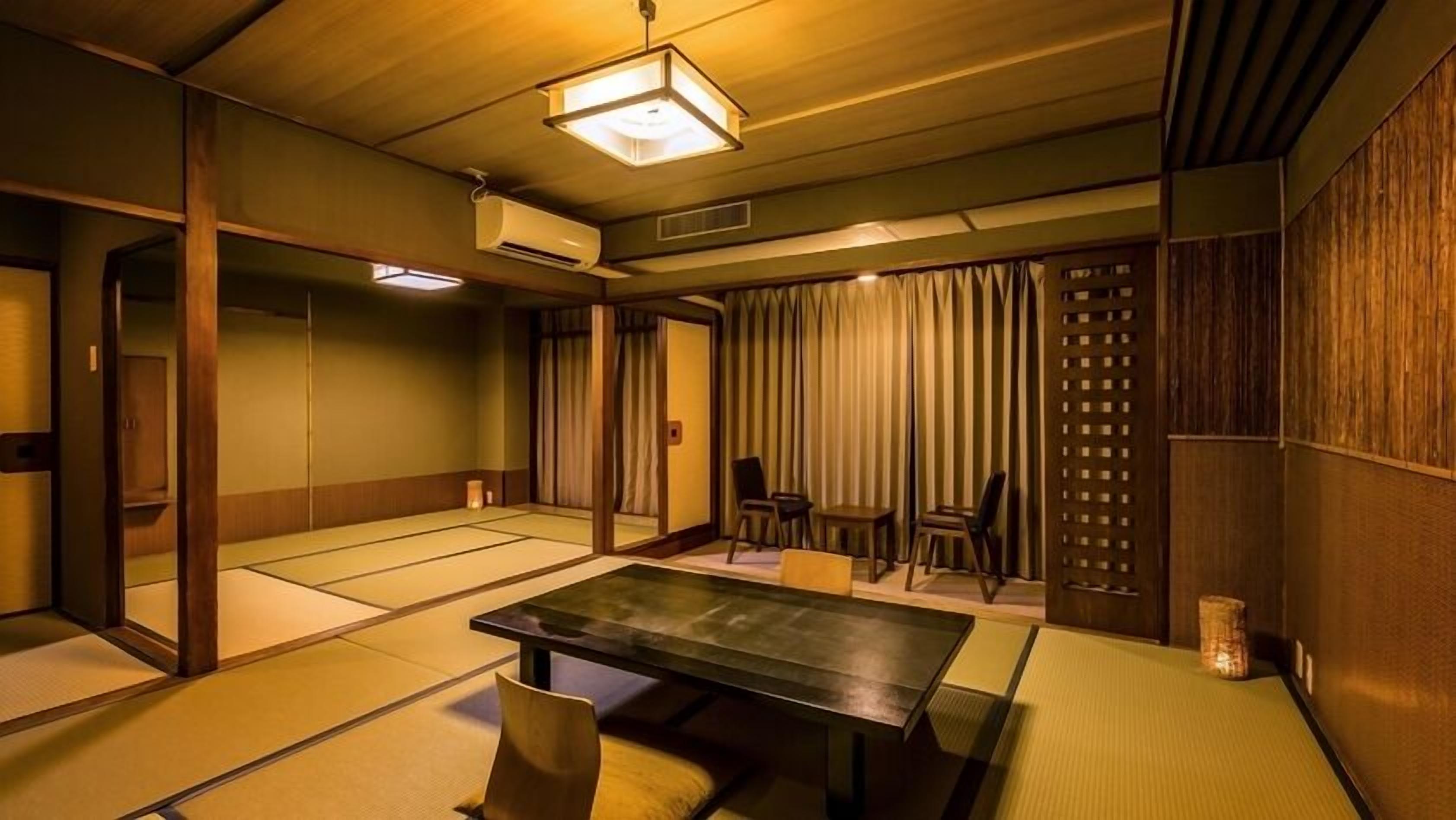 A tatami mat room with a low table, chairs, and a sliding door.