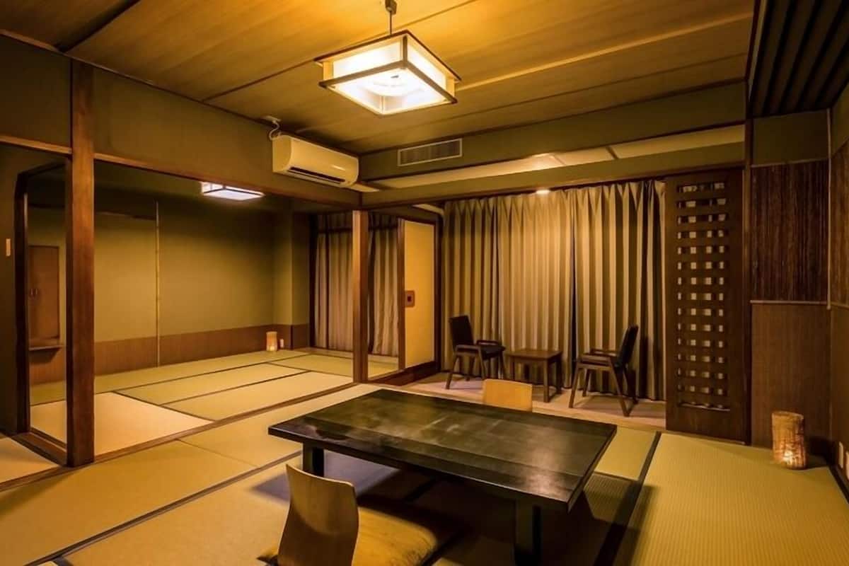 A tatami mat room with a low table, chairs, and a sliding door.