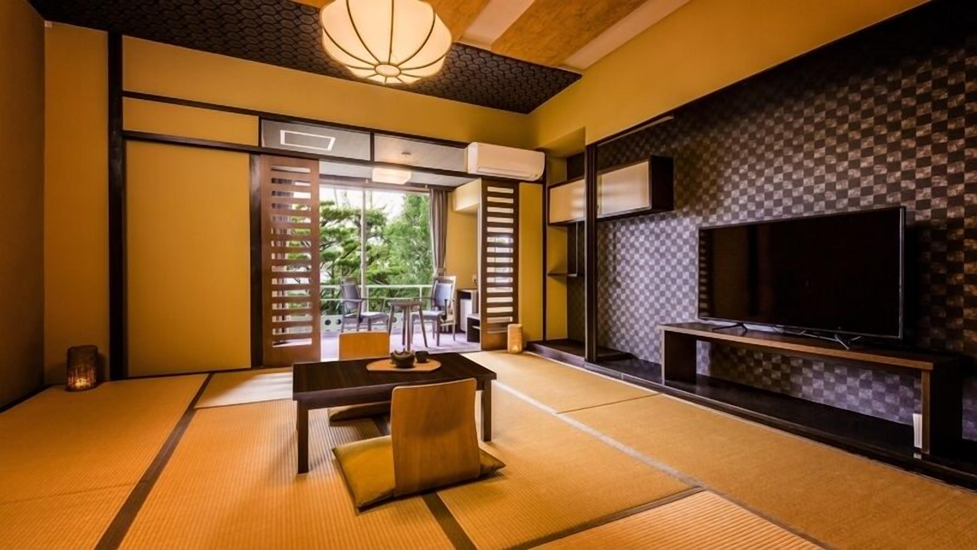 A traditional Japanese room with tatami flooring, a low table with cushions, sliding doors, a television, and a view of greenery outside.