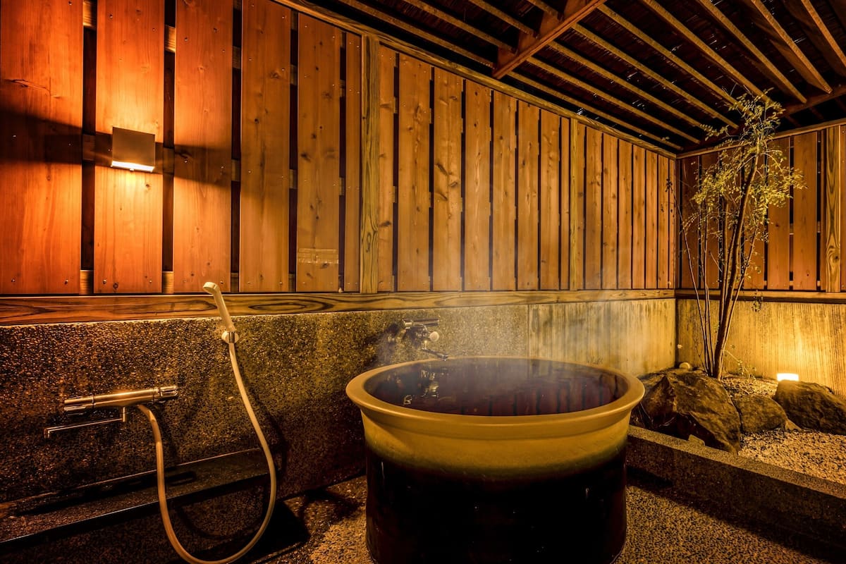 A hot spring bath area with wooden walls and a stone basin.