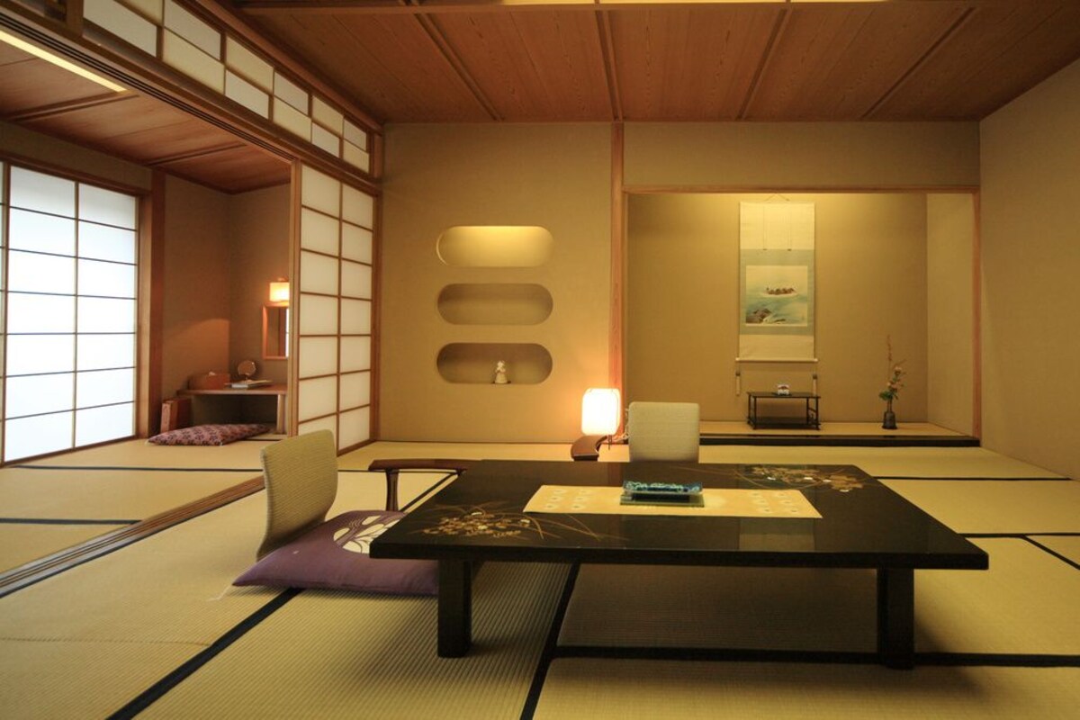 A tatami mat room with a low table, cushions, and a sliding door.