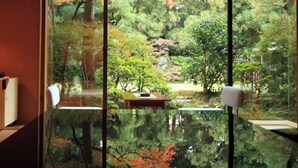 A room with a glass table, chairs, and a view of a garden through the glass. - Ureshino Onsen Taishouya (Ureshino)