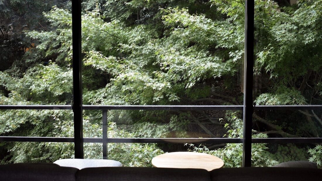 A room with a large window, a wooden table, and a sofa.