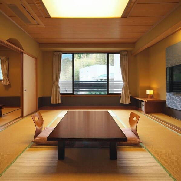 A traditional Japanese room with tatami flooring, a low wooden table, and sliding doors. - Hotel Zuiyo (Atami)