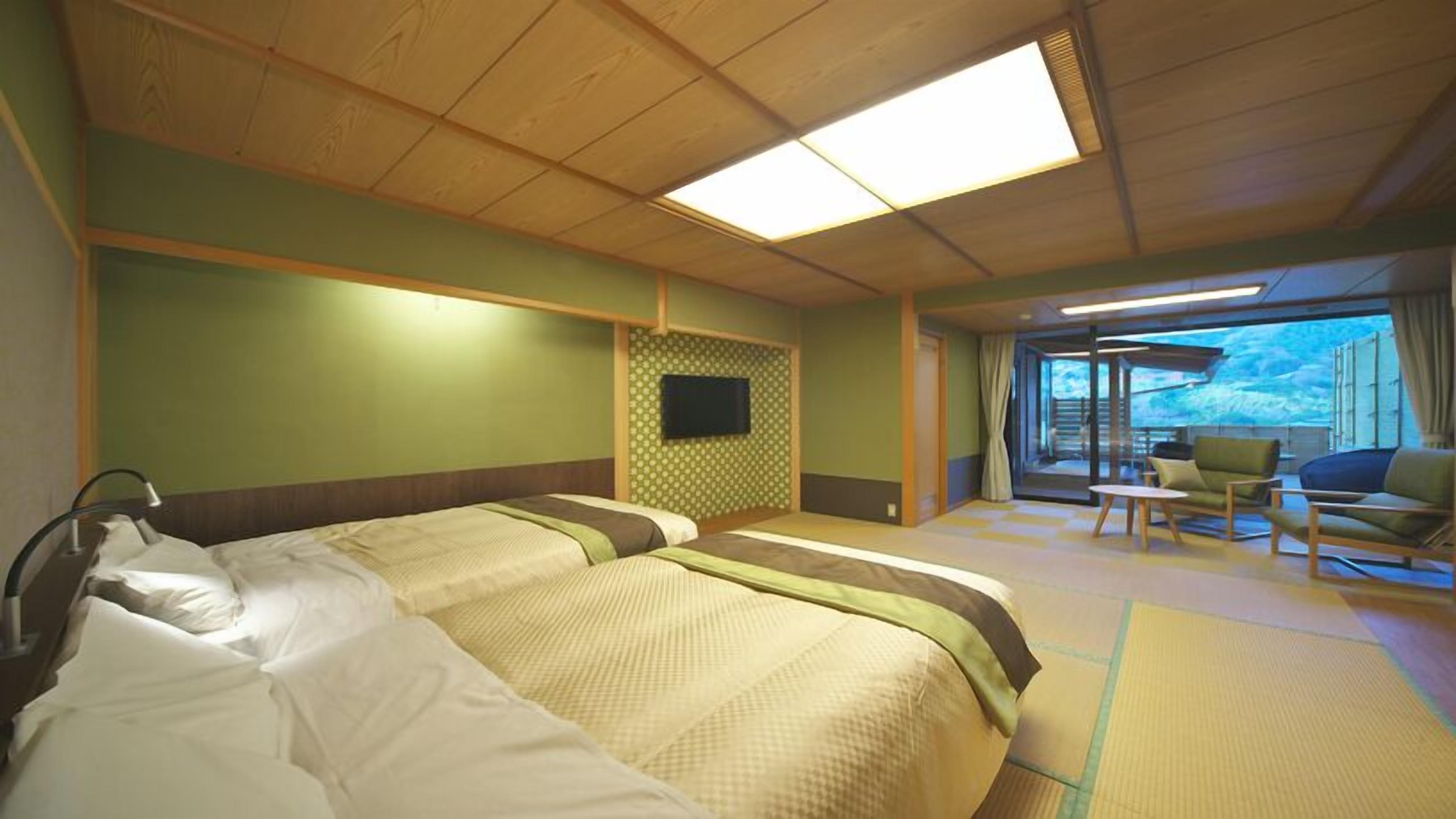 A hotel room with two beds, a TV, a seating area with a view, and a large window.
