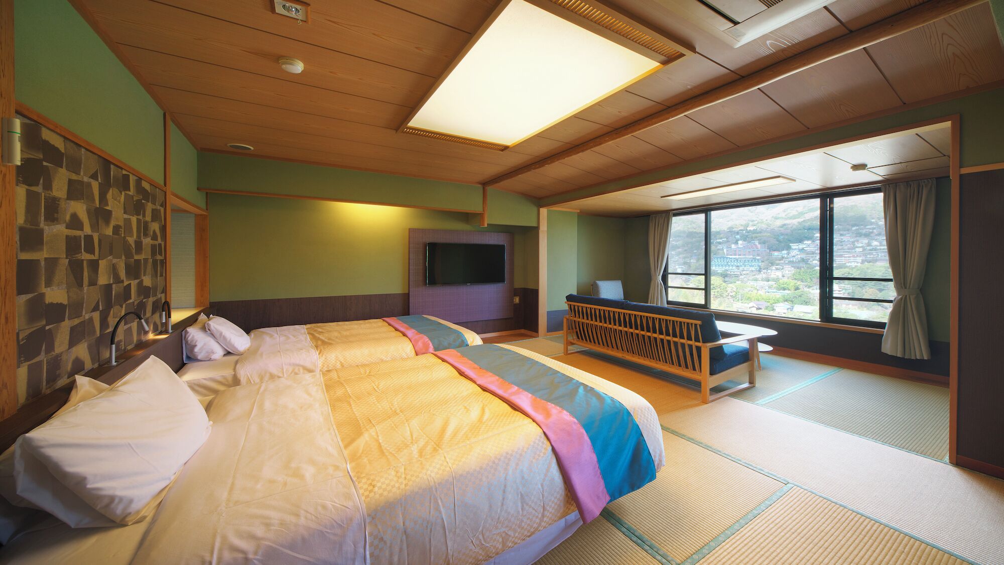 A hotel room with a large bed, a TV, a sofa, and a view of the outside.