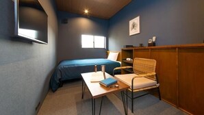 Une chambre à coucher comprenant un lit, un bureau, une chaise, une fenêtre et une étagère fixée au mur.
