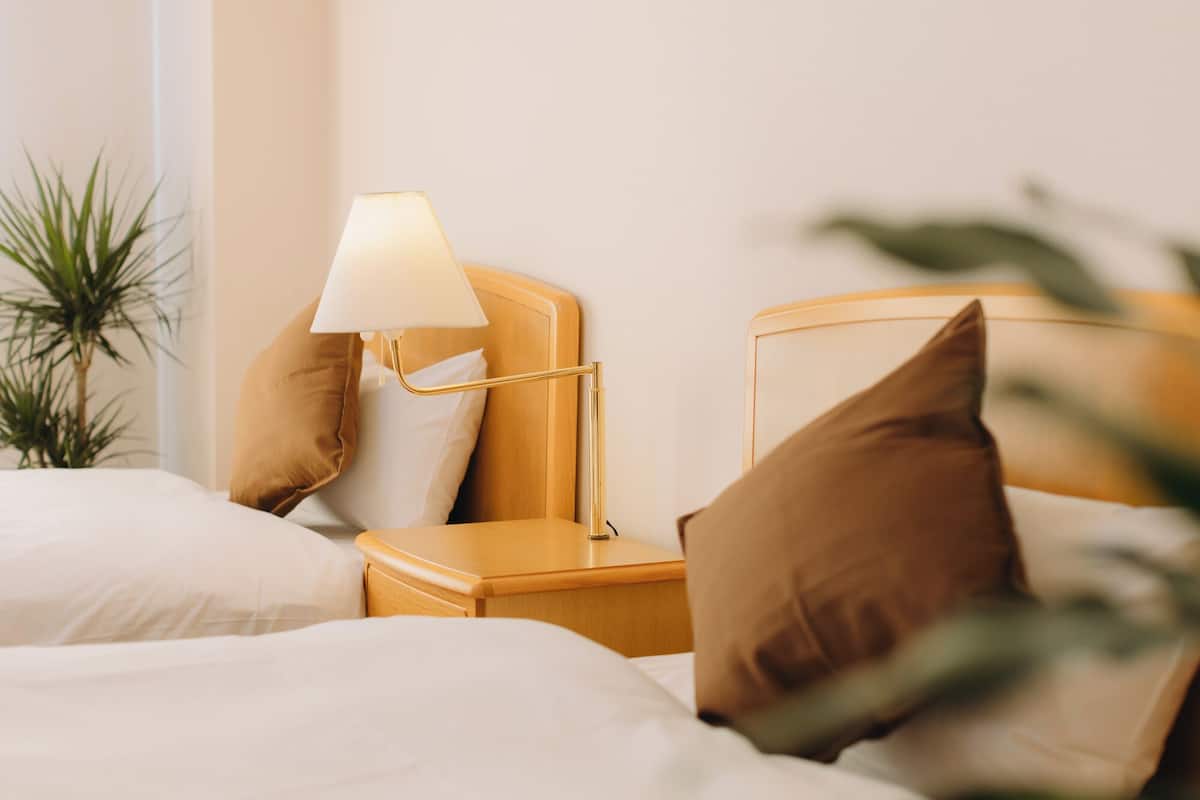 Un lit bien fait, avec des draps blancs, une lampe de chevet et deux oreillers.