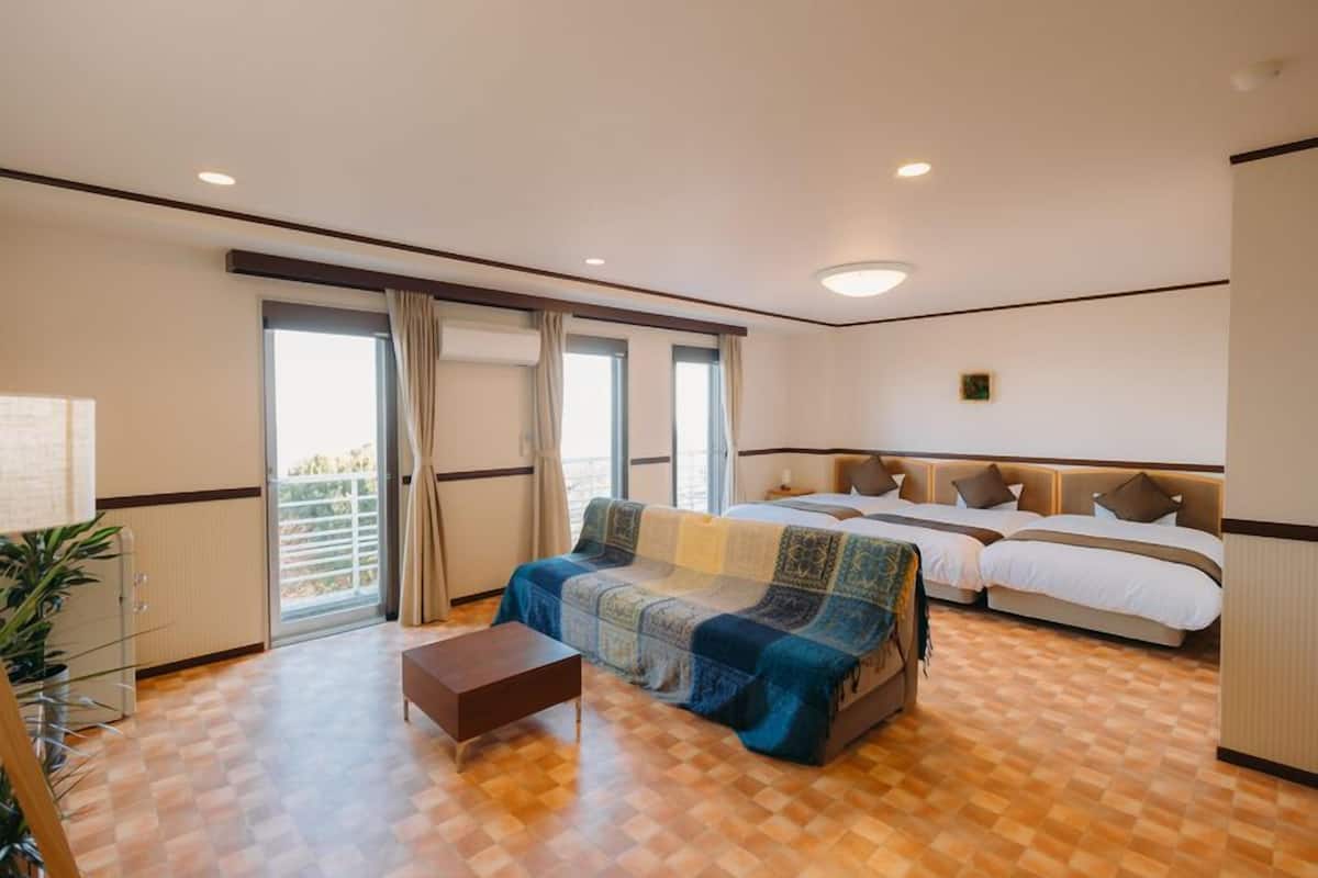 Une chambre d’hôtel avec un sol à carreaux, un canapé, un lit avec une tête de lit et une petite table.