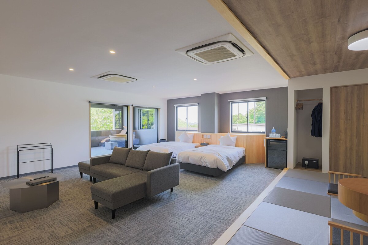 A modern hotel room with a sofa, a bed, a desk, and a wardrobe.