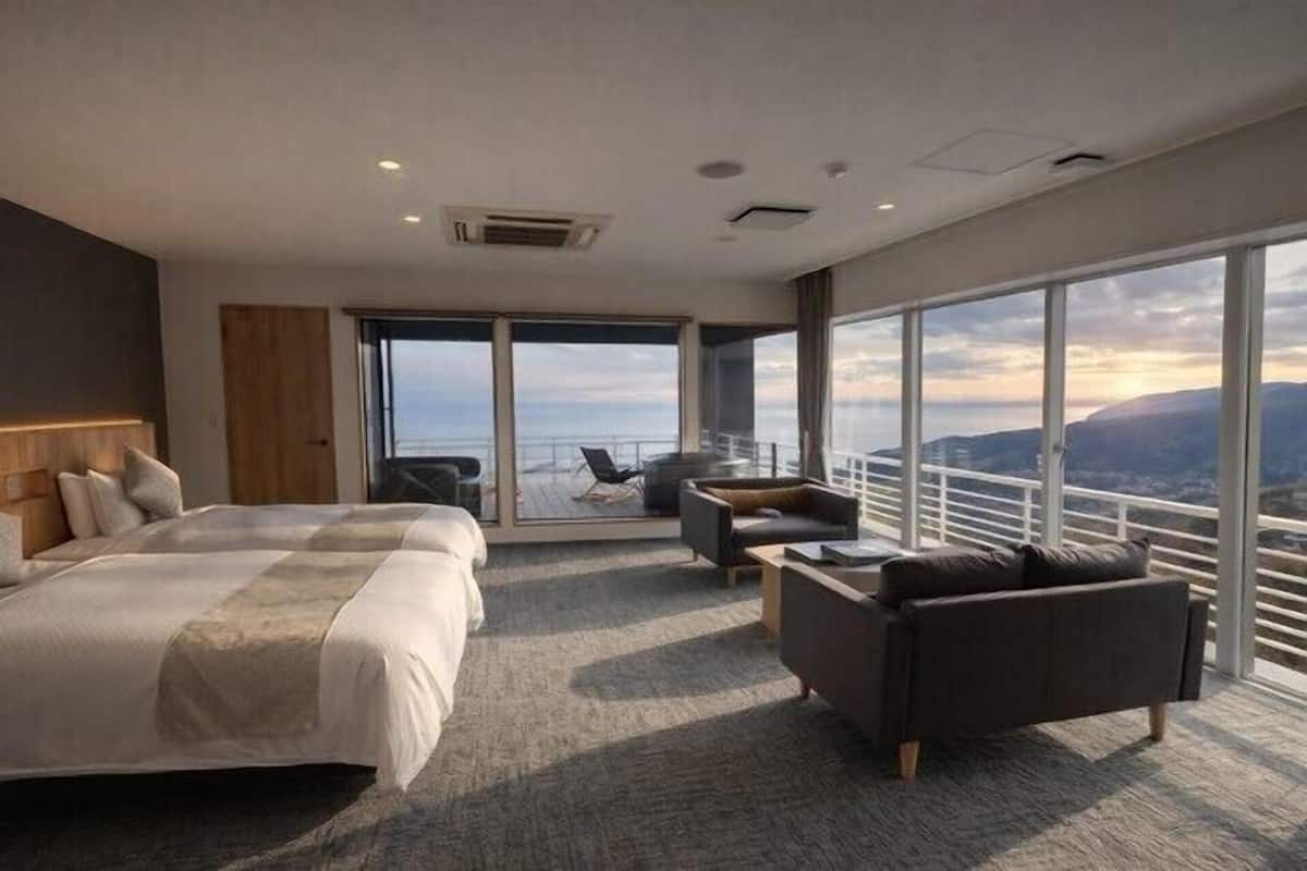 Une chambre d’hôtel moderne avec un grand lit, un canapé et un balcon offrant une belle vue.
