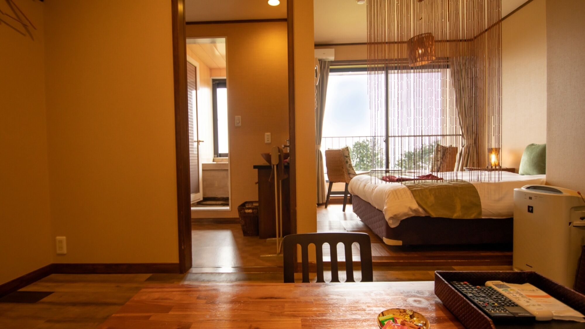 A hotel room with a bed, a desk with a computer, a chair, and a window with a view.