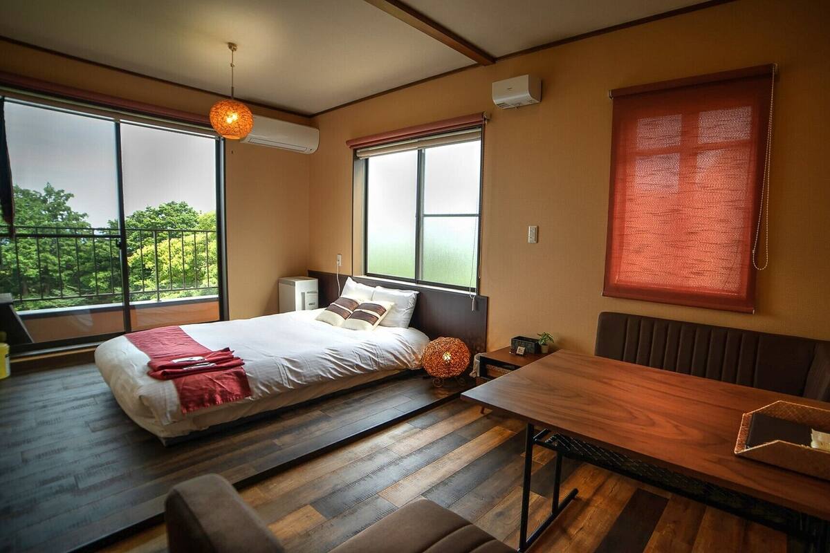 A bedroom with a bed, bedside table, and a window with a view.