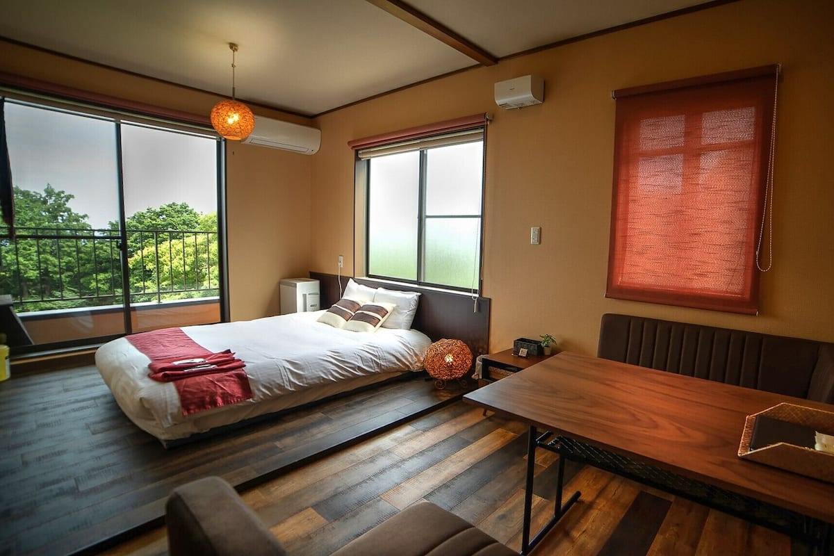 A bedroom with a bed, bedside table, and a window with a view.