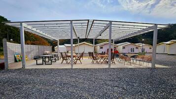 A covered outdoor seating area with tables and chairs, surrounded by tents.