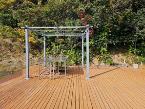 A wooden deck with a metal pergola structure, two tables, and a bench. - Sloth Glamping <tsushima> (Tsushima)