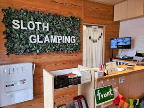 A room with a sign reading 'SLOTH GLAMPING,' a computer monitor, a desk with various items, and a map on the wall. - Sloth Glamping <tsushima> (Tsushima)