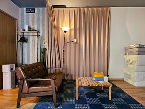A cozy room with a leather sofa, a wooden coffee table, a floor lamp, and a bed with pillows. - Sloth Glamping <tsushima> (Tsushima)