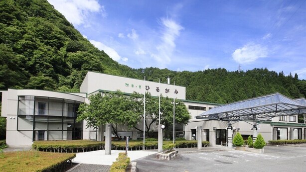 A modern building with a curved facade, a covered entrance, and a parking area.