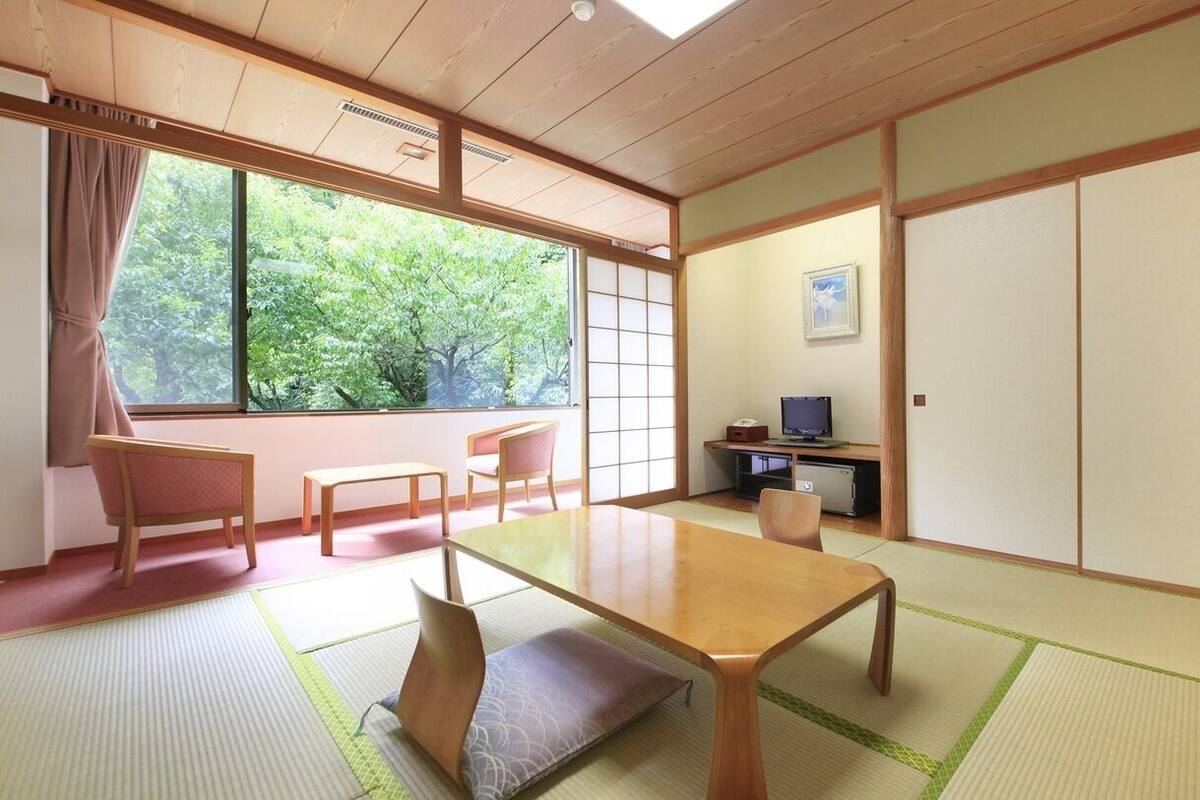 Una habitación japonesa tradicional con suelo de tatami, una mesa baja y puertas correderas.