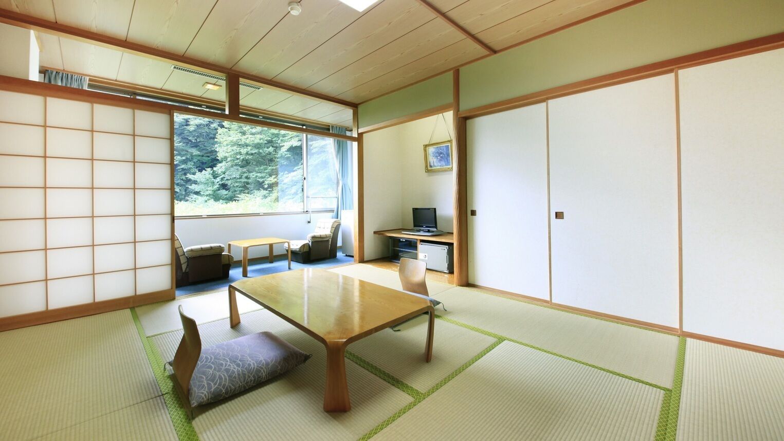 A traditional Japanese room with tatami flooring, a low table, a sofa, and sliding doors.
