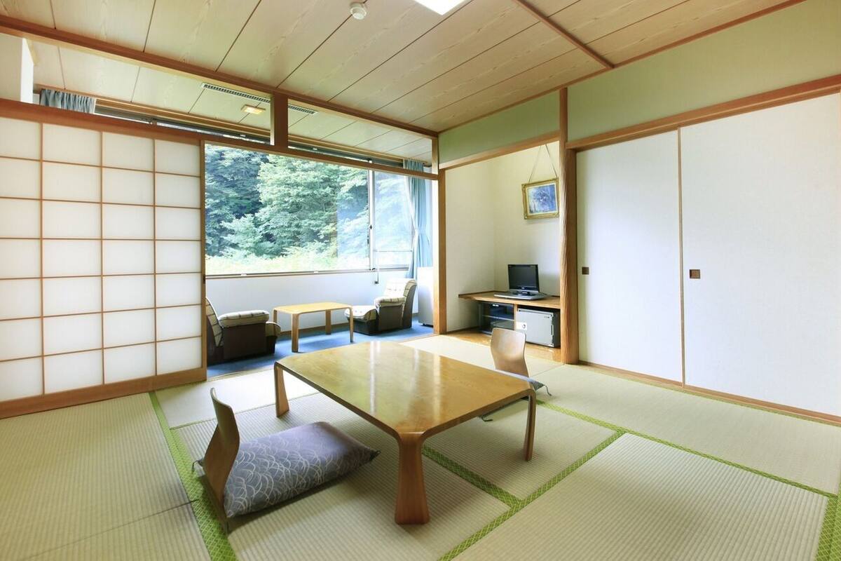 Una habitación japonesa tradicional con suelo de tatami, una mesita baja, un sofá y puertas correderas.
