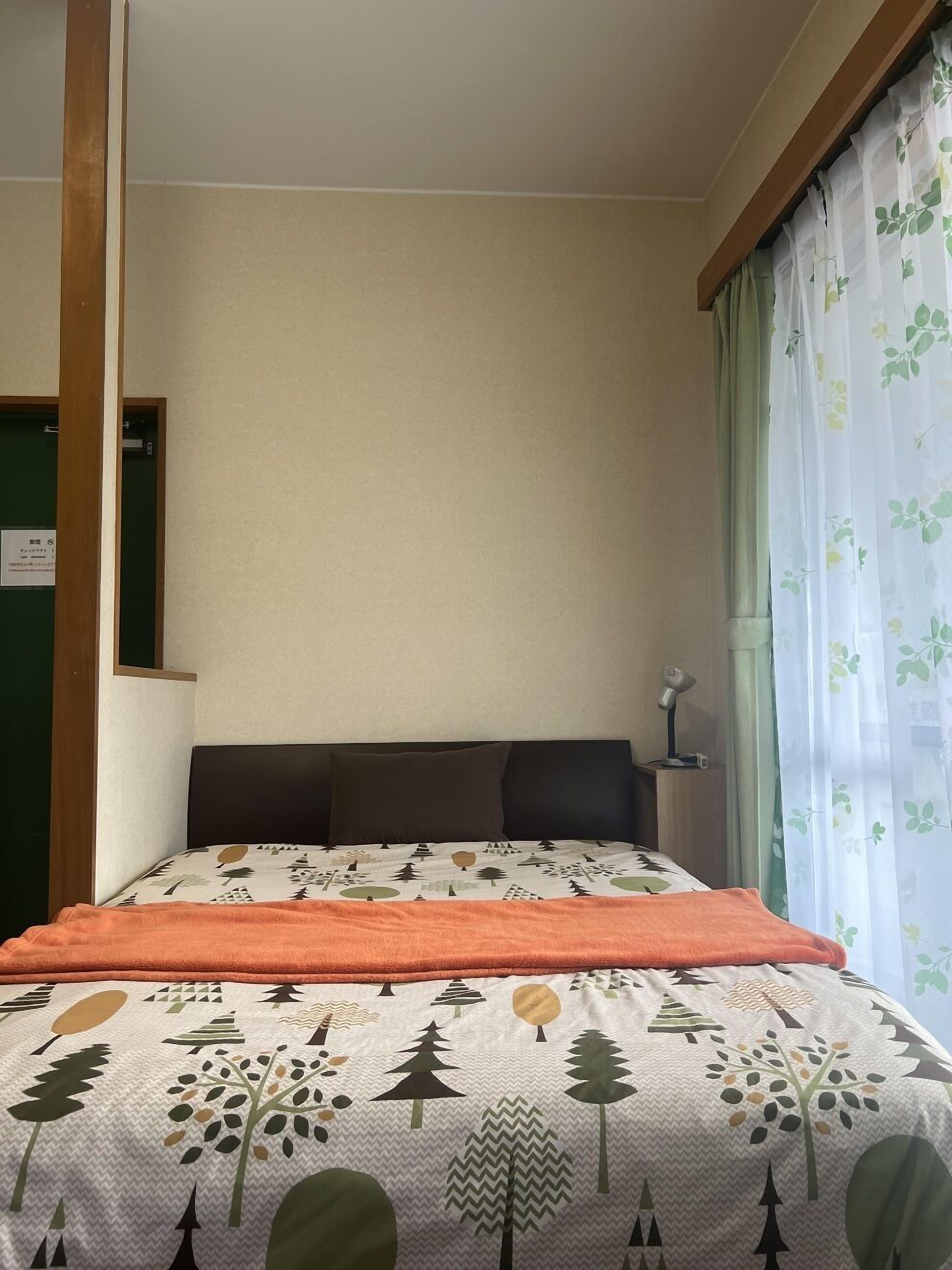 Een kamer met een bed, een bureau en een raam met gordijnen.