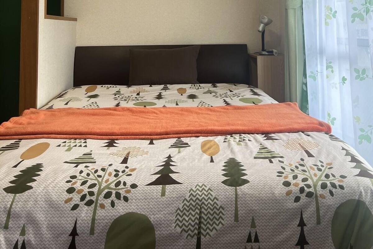 Ein Zimmer mit einem Bett, einem Schreibtisch und einem Fenster mit Vorhängen.