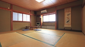 Una stanza con tatami, una televisione, un tavolino e una porta scorrevole.