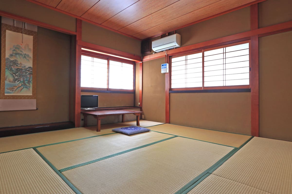 Una habitación japonesa tradicional con suelo de tatami, un televisor y una pintura en la pared.