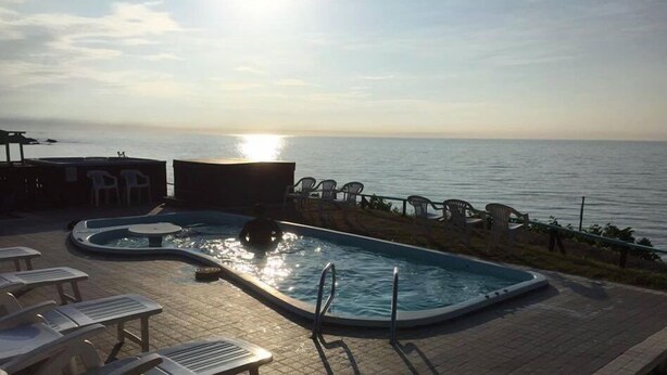 A swimming pool with lounge chairs and a view of the sea. - Sado Seaside Villa (Sado)