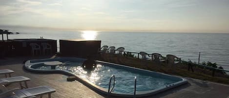 A swimming pool with lounge chairs and a view of the sea.