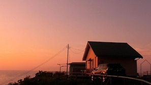A coastal house with a car parked outside, a small dock, and a power line.