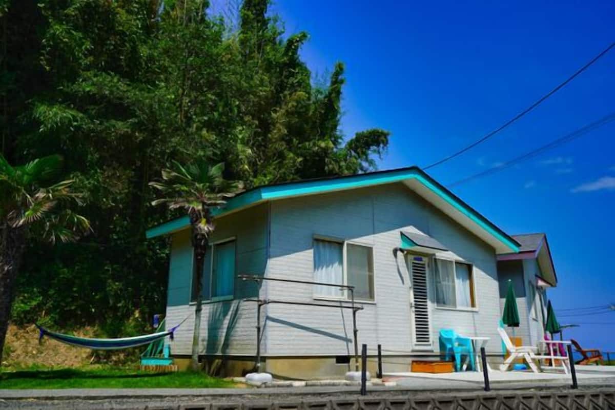 A single-story house with a porch, a hammock, and outdoor seating.