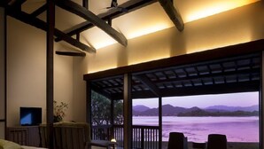 A bedroom with a large bed, a TV, and a view of a body of water and mountains. - Mizube No Hanare Calme (Kyotango)