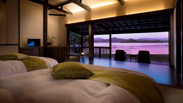 A bedroom with two beds, a desk, and a view of a lake at dusk. - Mizube No Hanare Calme (Kyotango)
