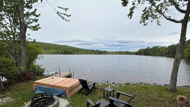 Une terrasse au bord du lac, avec un foyer, des sièges et une vue sur le lac.