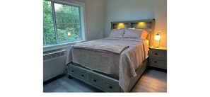 Une chambre à coucher comprenant un lit, des tables de chevet, une fenêtre avec vue et un radiateur.