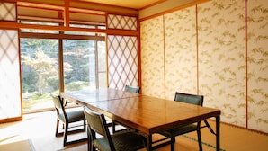 Una tradizionale stanza giapponese con pavimento in tatami, un tavolo di legno e porte scorrevoli con motivi in bambù.