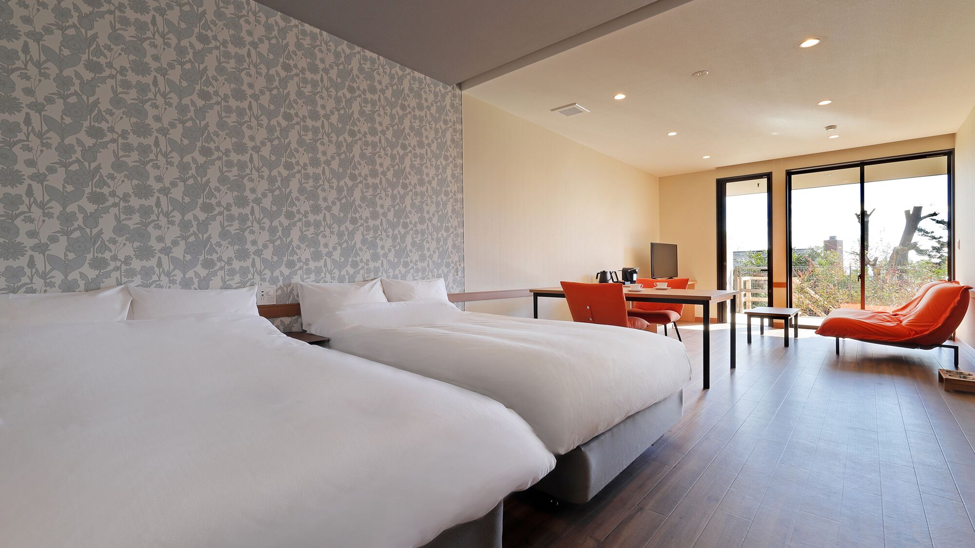 A hotel room with a large bed, a desk, a chair, and a view through a large window.