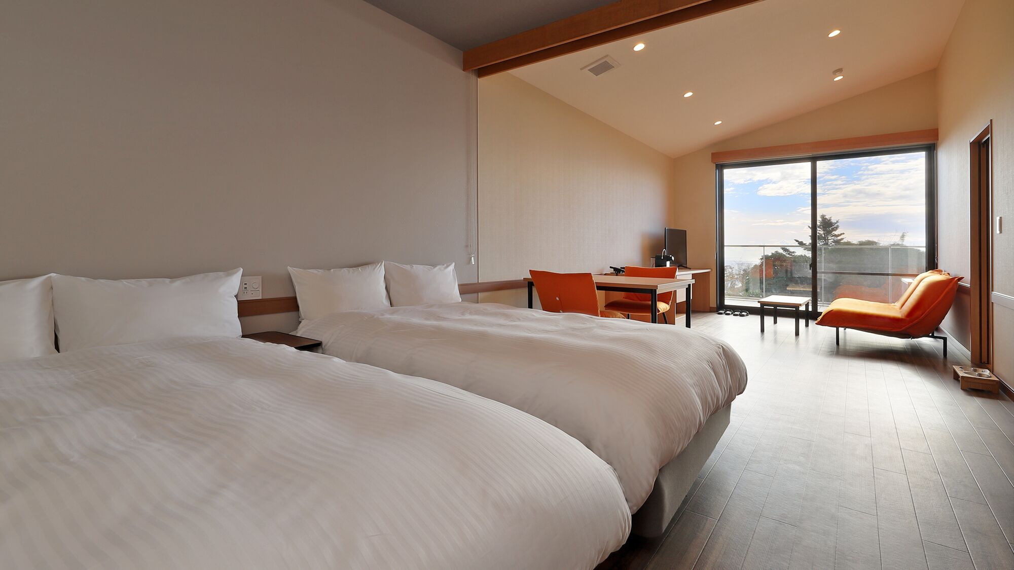 A hotel room with two large beds, a desk, a chair, and a large window with a view.