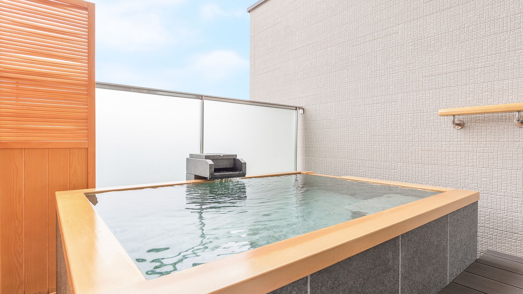 A hot tub with a wooden frame, a stone wall, and a wooden panel on the left.