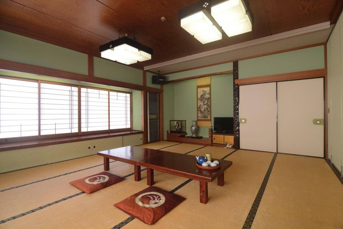 A traditional Japanese room with tatami flooring, a low wooden table, a television, and sliding doors.
