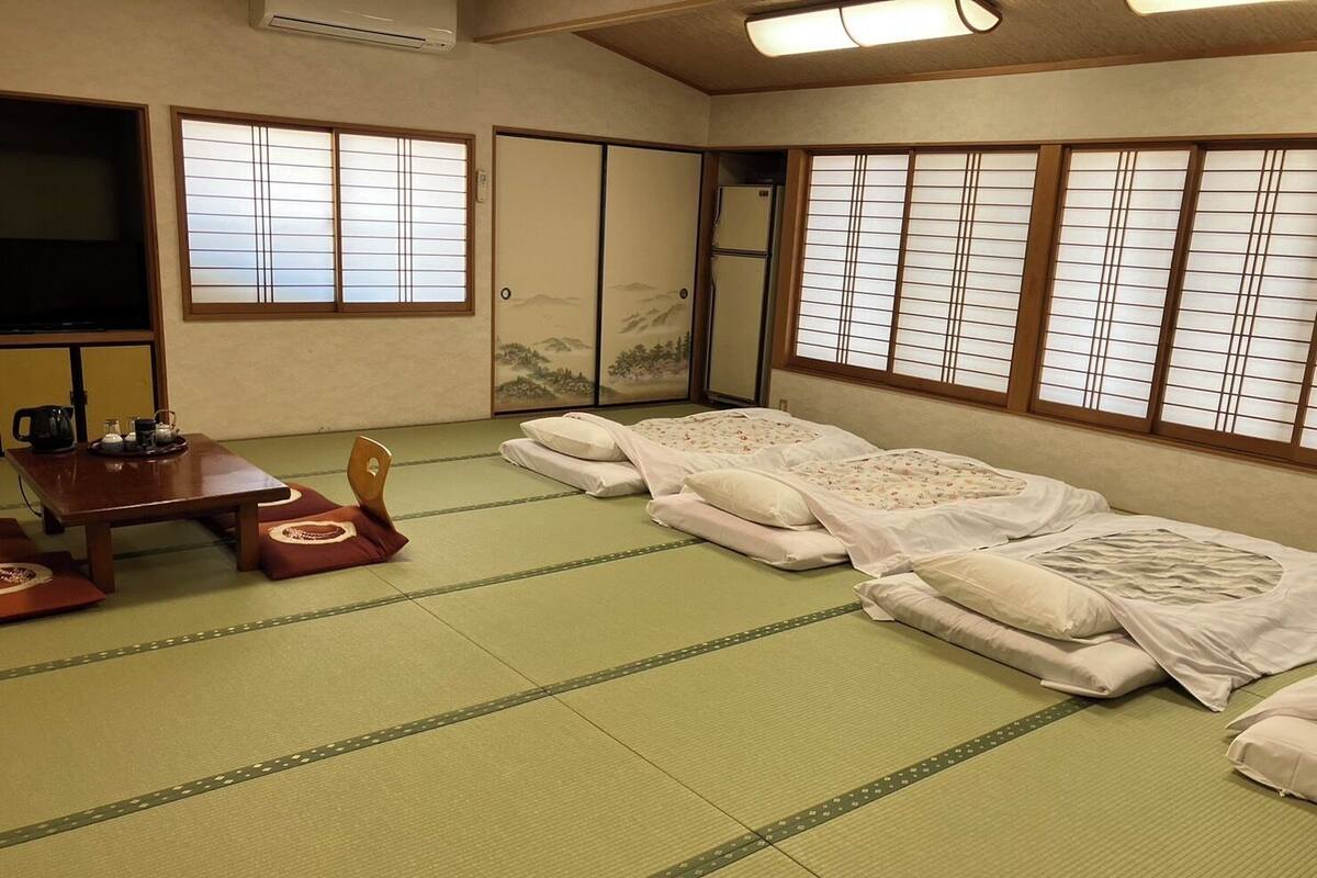 A traditional Japanese room with tatami flooring, a low table with a tea set, and futon beds.