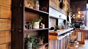 A rustic interior with wooden shelves, potted plants, and a bar area. - Tabi Yado Rantan (Shinano)