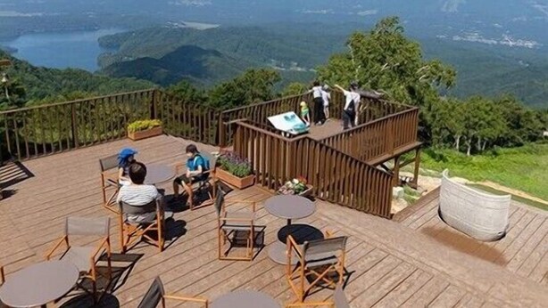 A wooden deck with outdoor seating and a view of a mountainous landscape. - Tabi Yado Rantan (Shinano)