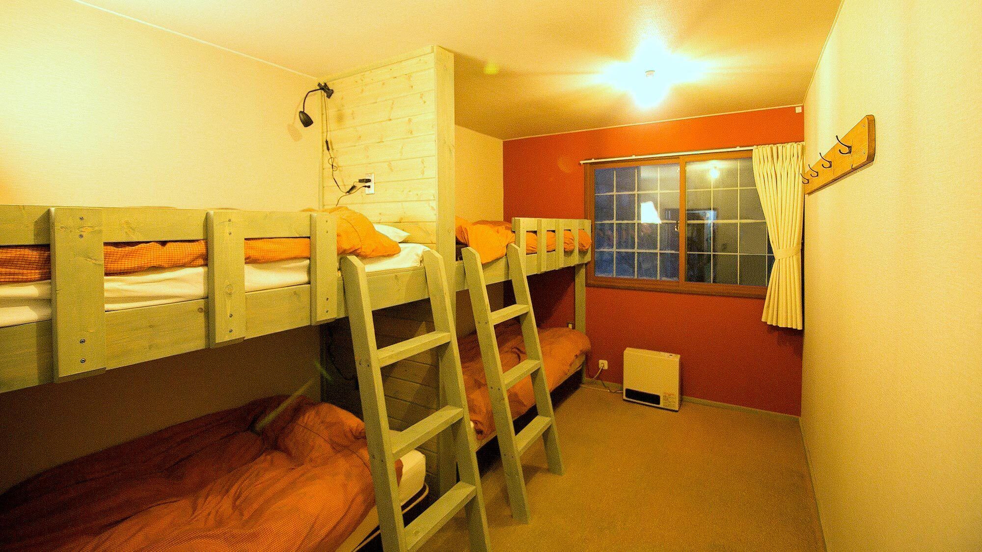 A bunk bed room with a window, a heater, and a coat rack.