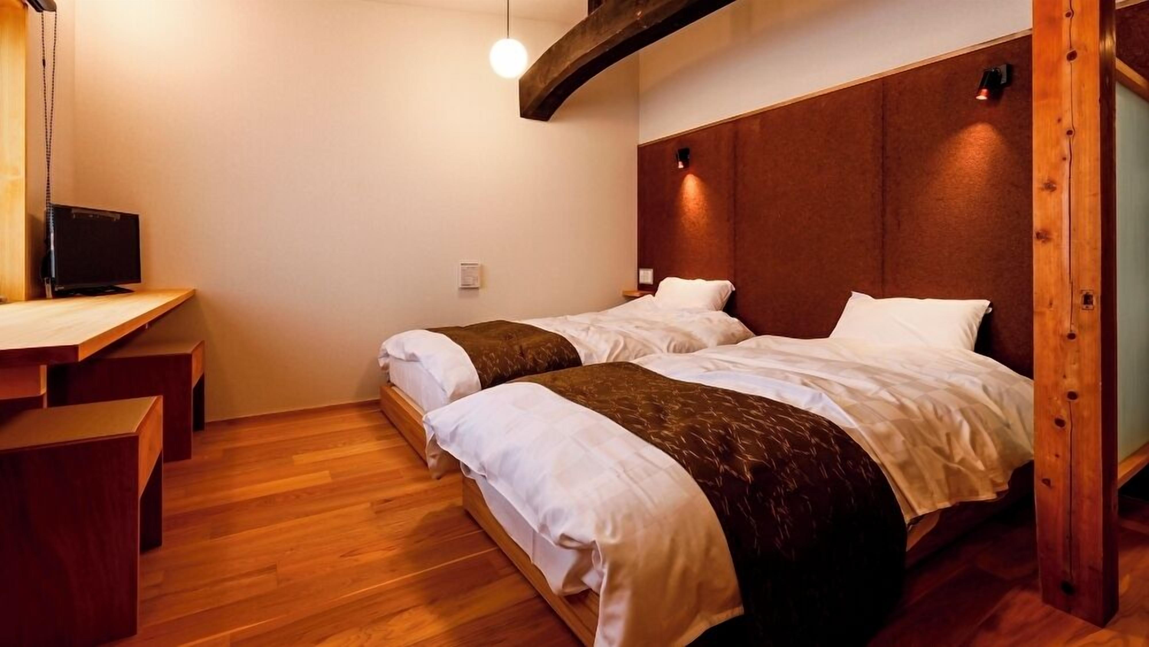 Habitación de hotel con dos camas, un escritorio de madera y televisor.