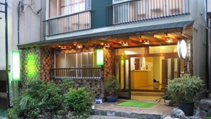 A two-story building with a balcony, a wooden porch, and a green awning. - Kusatsu Onsen Ryokan Yakumo (Kusatsu)