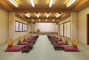 Un salón de conferencias con filas de sillas, un escenario y paneles de madera.